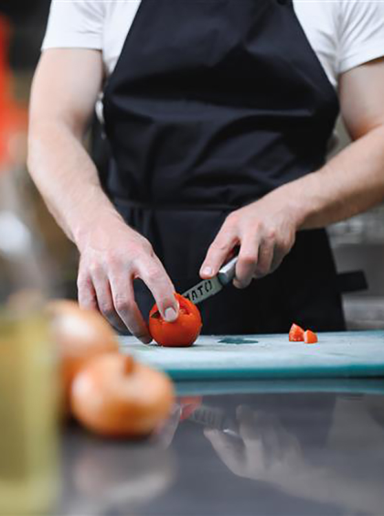 Koch schneidet Tomate