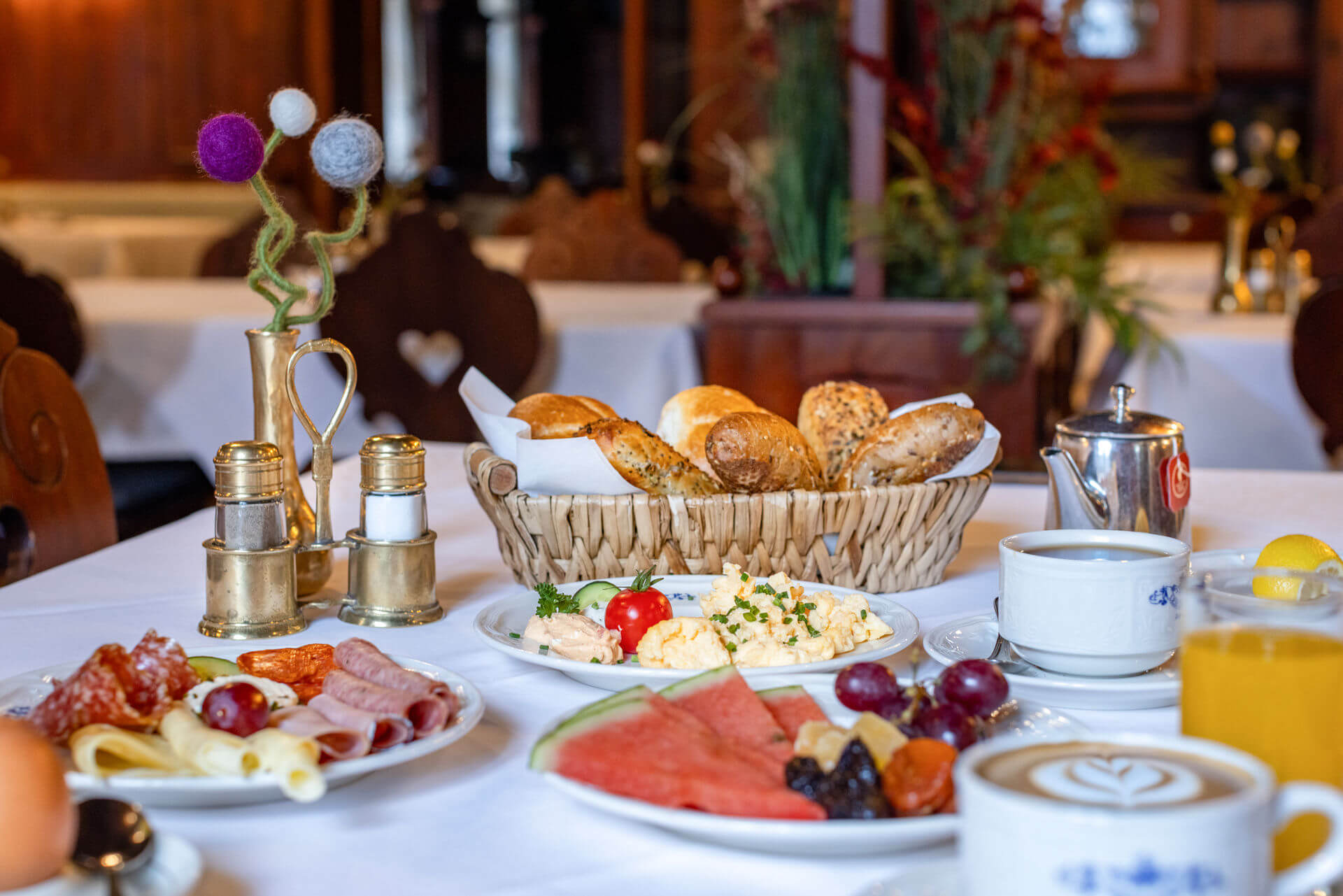 Gedeckter Frühstückstisch mit Wurst, Brot, Melone, Kaffee, Saft